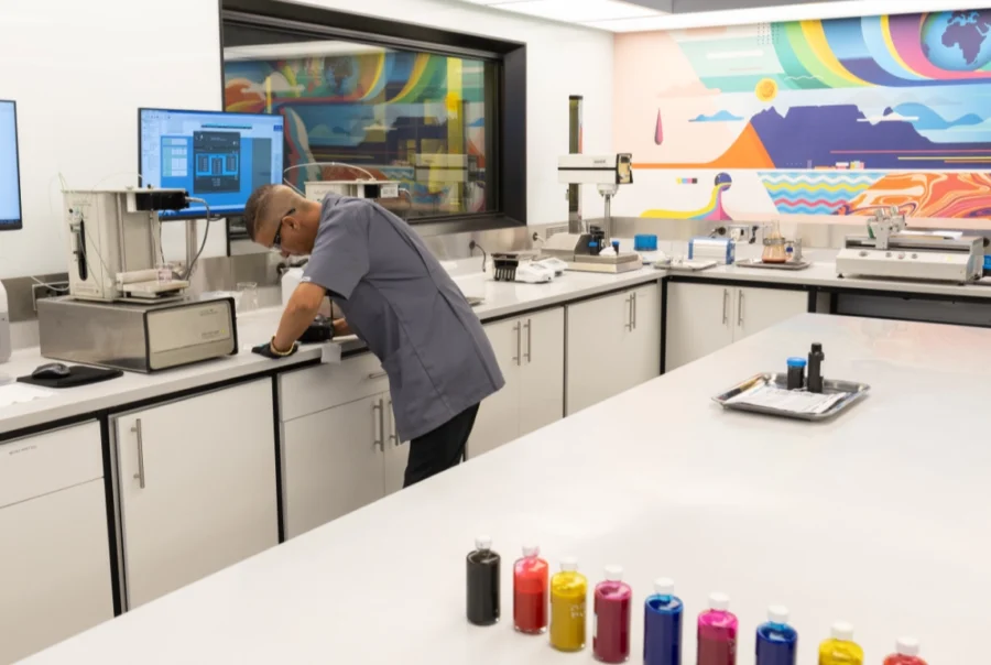 Laboratory technician working with digital printing inks in a creative development lab at NUtec Digital Ink, showcasing ink testing with colour bottles and testing equipment.